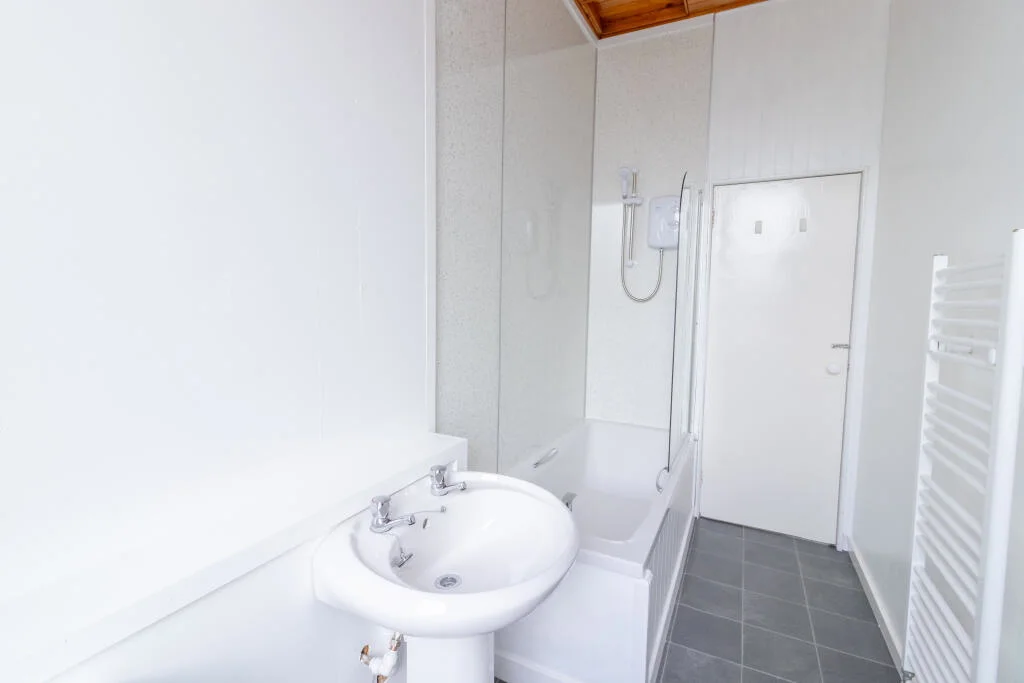 Bathroom with bath, electric shower and heated towel rail