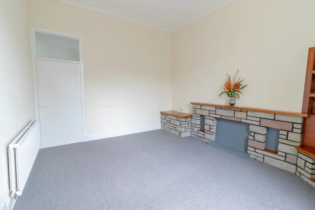 Living room with neutral decor, grey carpet and stone fireplace
